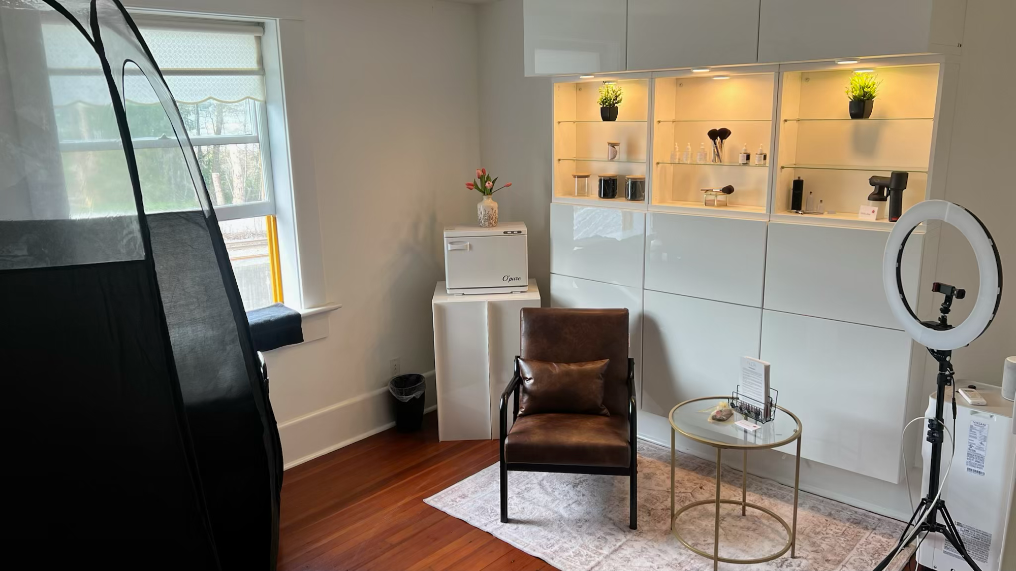 Tan & Glow studio interior with spray tan booth, product display, and seating area